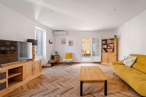 a living room with a yellow couch and a flat screen tv at Maison l’Oustaou Cornillonnais in Cornillon-Confoux