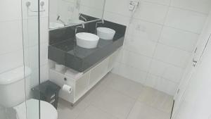 a white bathroom with two sinks and a toilet at Aiezza Hotel in Barcarena
