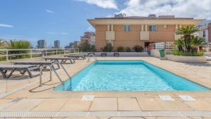 a swimming pool with picnic tables and a building at Le Studio des Deux Frontières in Beausoleil