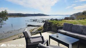 a deck with a couch and chairs next to a body of water at Cozy seaside cottage SE09169 in Myggenäs +15 photos
