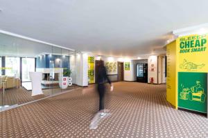 a person walking through a room with a yellow wall at SLEEEP Hotel Vösendorf in Vösendorf