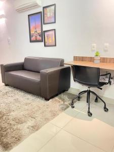 a couch sitting in a room with a desk and a computer at Flat inteiro Ônix Bueno in Goiânia