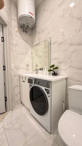 a white bathroom with a sink and a washing machine at Raduga Resort Orion in Chon-Sary-Oy