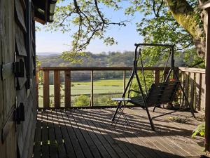 a swinging chair on a porch with a view at Cosy Treehouse in Pontypool +41 photos