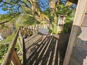 a wooden deck with a bench sitting on it at Cosy Treehouse in Pontypool