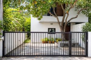 a black gate in front of a house with a tree at Anas house in Lipa Noi in Lipa Noi