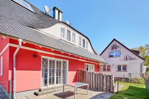 a red and white house with a bench in front of it at Haus Strandbrise Graal-Müritz in Graal-Müritz