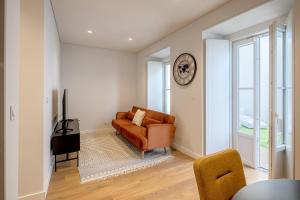 a living room with a couch and a clock on the wall at Glasgow Industrial 2BR apartment in Caparica
