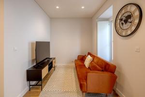 a living room with a couch and a clock on the wall at Glasgow Industrial 2BR apartment in Caparica