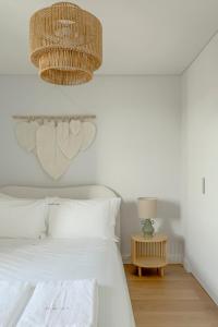 a bedroom with a white bed and a chandelier at Tulum Bohemian 2BR Apartment in Caparica