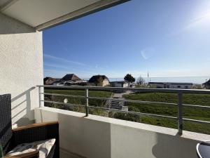 a balcony with a view of a field and the ocean at Strandhotel - 19 "Sardinenbüchse" in Dahme