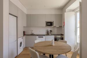 a kitchen with a wooden table and white cabinets at Vienna 1BR Calm & Cozy Escape in Caparica