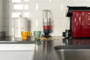 a counter with coffee cups and a blender on it at Vienna 1BR Calm & Cozy Escape in Caparica +29 photos