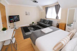 a bedroom with a bed and a couch and a television at Greenhithe Guest House in Stonewood