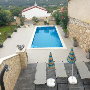 a swimming pool with two umbrellas on a patio at Apartmani Lea in Bribir