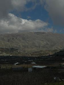 a view of a hill with a mountain in the background at Cherry trees & mount Hermon views,near ram pool in Majdal Shams