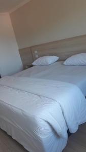 a bedroom with two beds with white sheets and pillows at Flat 55 Goiania in Goiânia