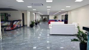 an office lobby with white furniture and potted plants at Flat 55 Goiania in Goiânia