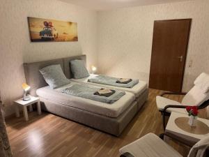 a small room with two beds and a chair at ESER Hotel Apartment in Hertingen +10 photos