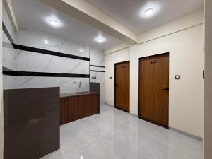 a large kitchen with a sink and two wooden doors at Shreya Bungalow Mahabaleshwar in Mahabaleshwar