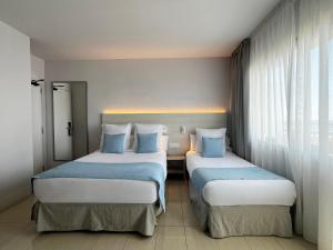 two beds in a hotel room with blue pillows at Hotel Excelsior in Lloret de Mar