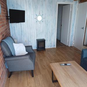 a living room with a chair and a fireplace at Waters edge in Amroth