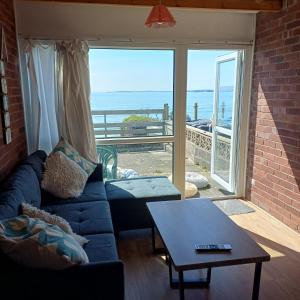 a living room with a couch and a view of the ocean at Waters edge in Amroth
