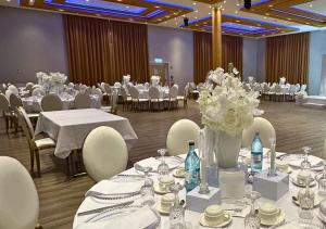 a banquet hall with white tables and chairs and flowers at Steinberger Hof in Dietzenbach