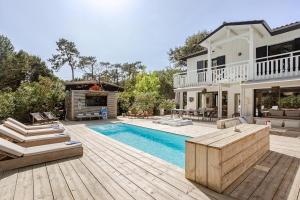 a home with a swimming pool and a house at Villa Lilas Cap-Ferret in Lège-Cap-Ferret