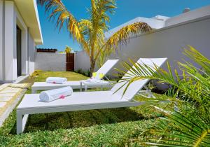 two white lounge chairs on the lawn of a house at Corail Bleu Private Villas by LOV in Bain Boeuf