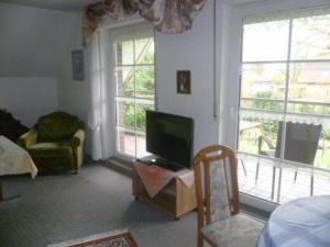 a living room with a tv and a chair and windows at Ferienwohnung Ewen 55038 in Filsum