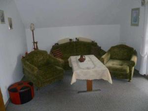 a living room with two chairs and a table at Ferienwohnung Ewen 55038 in Filsum +5 photos