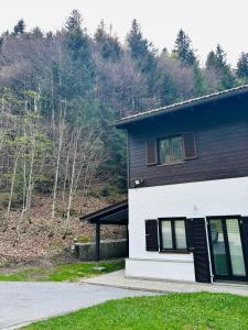 a white and black house with trees in the background at Apartment Auszeit im Ski- und Wandergebiet Spitzingsee - neu renoviert in Schliersee