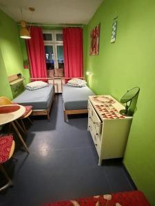 a green room with two beds and a table at Bazylika hostel in Warsaw