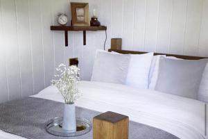 a bed with a vase of flowers on a table at Trethowels Grey Hidden hut in St Austell +3 photos