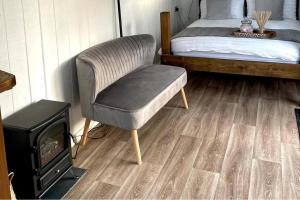 a bedroom with a chair and a bed and a stove at Trethowels Grey Hidden hut in St Austell