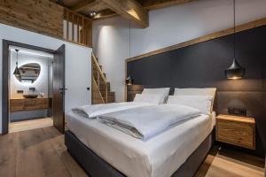 a bedroom with a large bed with white sheets at Kellnergut chalet Frieda in Mühlbach am Hochkönig