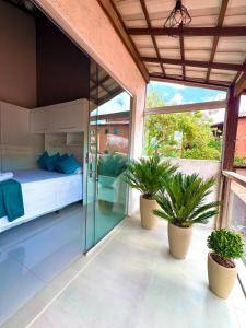 a bedroom with a bed and two potted plants at Serra do Cipó Casa Baru in Santana do Riacho