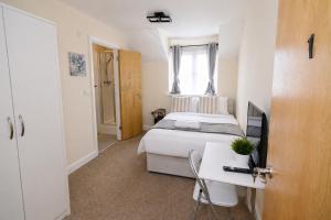 a bedroom with a bed and a desk and a television at Greenhithe Guest House in Stonewood