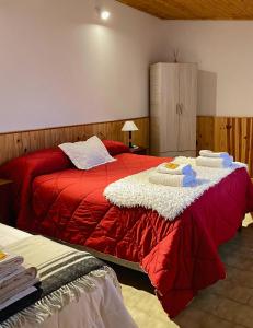 a bedroom with a red bed with towels on it at Departamento Quetro in Trevelín