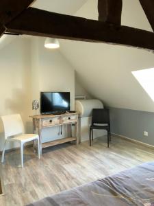 a bedroom with a tv and a desk with two chairs at Le nid marin in Étretat