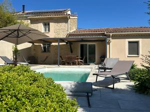 a pool with chairs and an umbrella next to a house at Villa Elara provençale avec piscine 4 étoiles in Sarrians