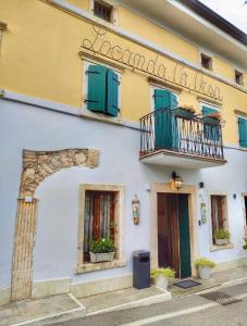 a white building with green windows and a balcony at Welcome Traveller Caorsa Rooms in Cavaion Veronese