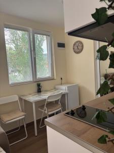 a kitchen with a desk and a table and two windows at Уют in Sandanski