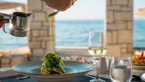 a table with a plate of food and a glass of wine at Canvas by Mitsis Cretan Village in Hersonissos