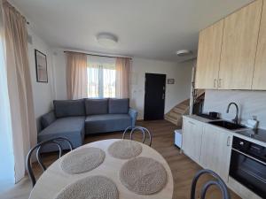a kitchen and living room with a table and a couch at Rewal Komfortowy Apartament 2 Sypialnie 10 min od Plaży Parking Taras Grill in Rewal