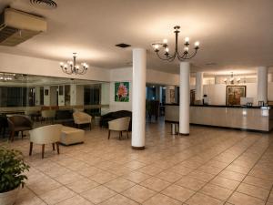 a lobby with columns and chairs and a table at Grand Hotel by MH in Termas de Río Hondo