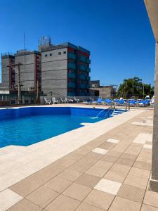 a swimming pool with chairs and buildings in the background at Grand Hotel by MH in Termas de Río Hondo