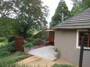 a garden with a white house with a patio at Pumula Luxury Camps in Lions River +25 photos