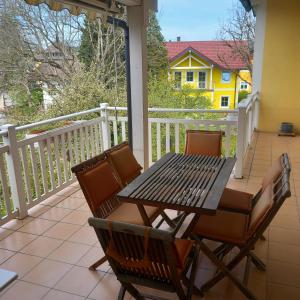 a table and chairs on a balcony with a yellow house at Seekirchen Zentrum in Seekirchen am Wallersee